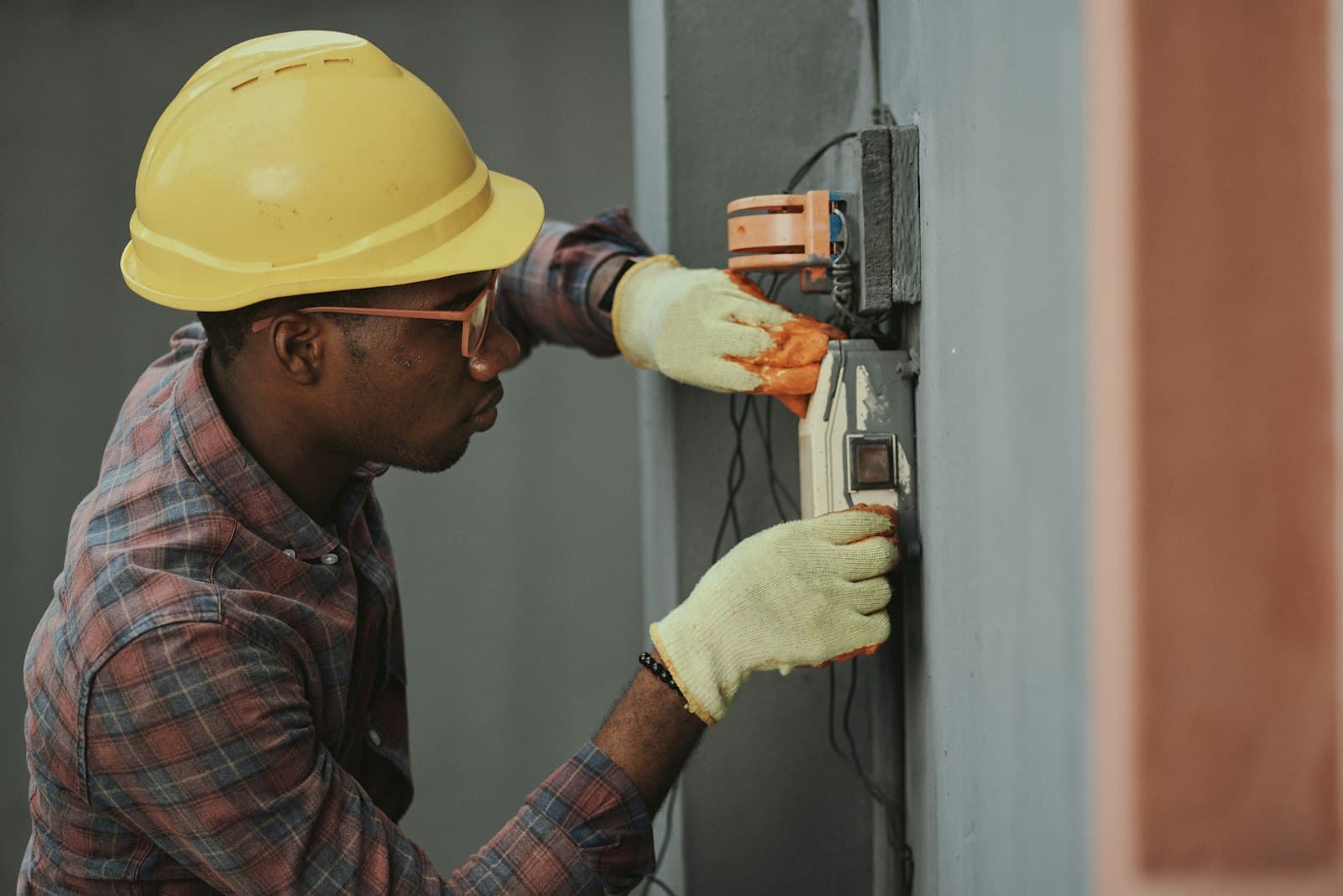 Technician in a hard hat installing an electrical fixture on a wall